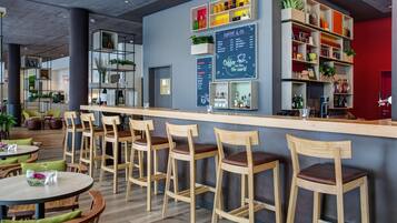 A modern bar area with wooden bar stools, a counter, and shelves with various items.