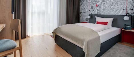 Camera d'albergo moderna con un letto grande, una scrivania e una parete con una mappa.