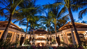 A resort with a pool, palm trees, and a covered area with seating. - The Anam Cam Ranh (Cam Lam)