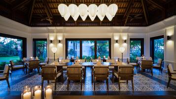 A spacious dining area with a long table, multiple chairs, and candle centerpieces.