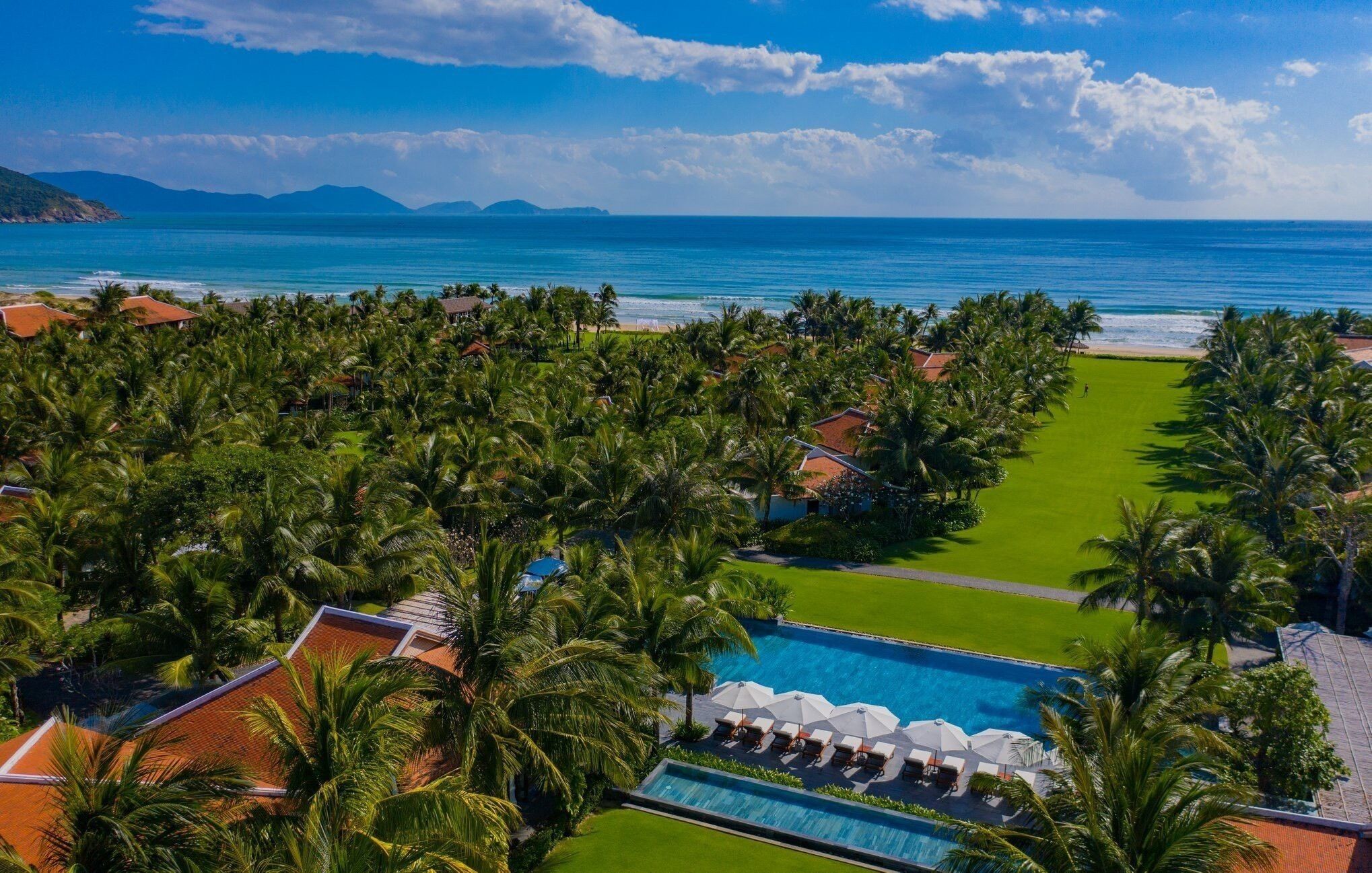 Ein Resort mit Pool, Palmen und Meerblick.