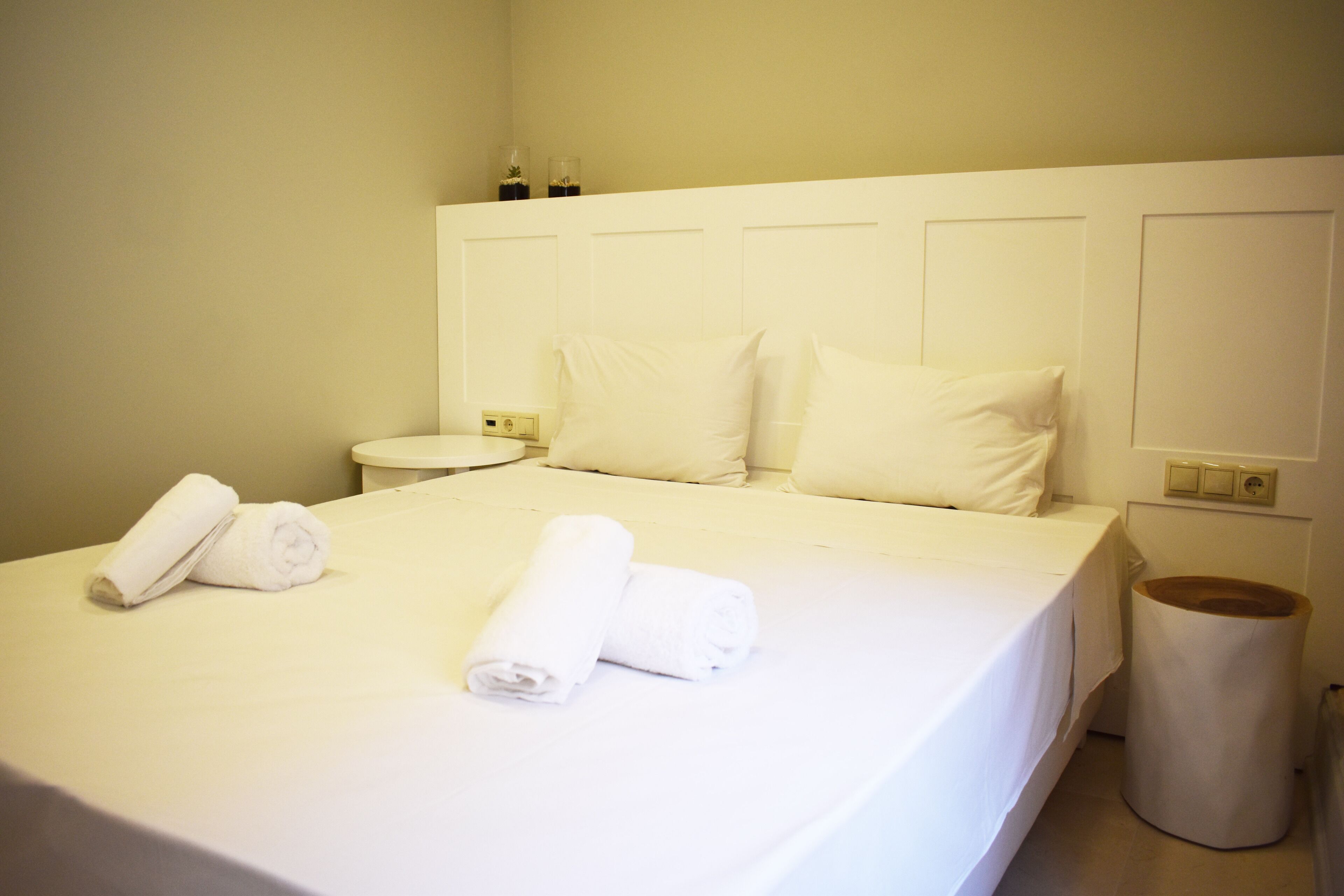 Una cama bien hecha con sábanas blancas y dos toallas enrolladas sobre la cama.