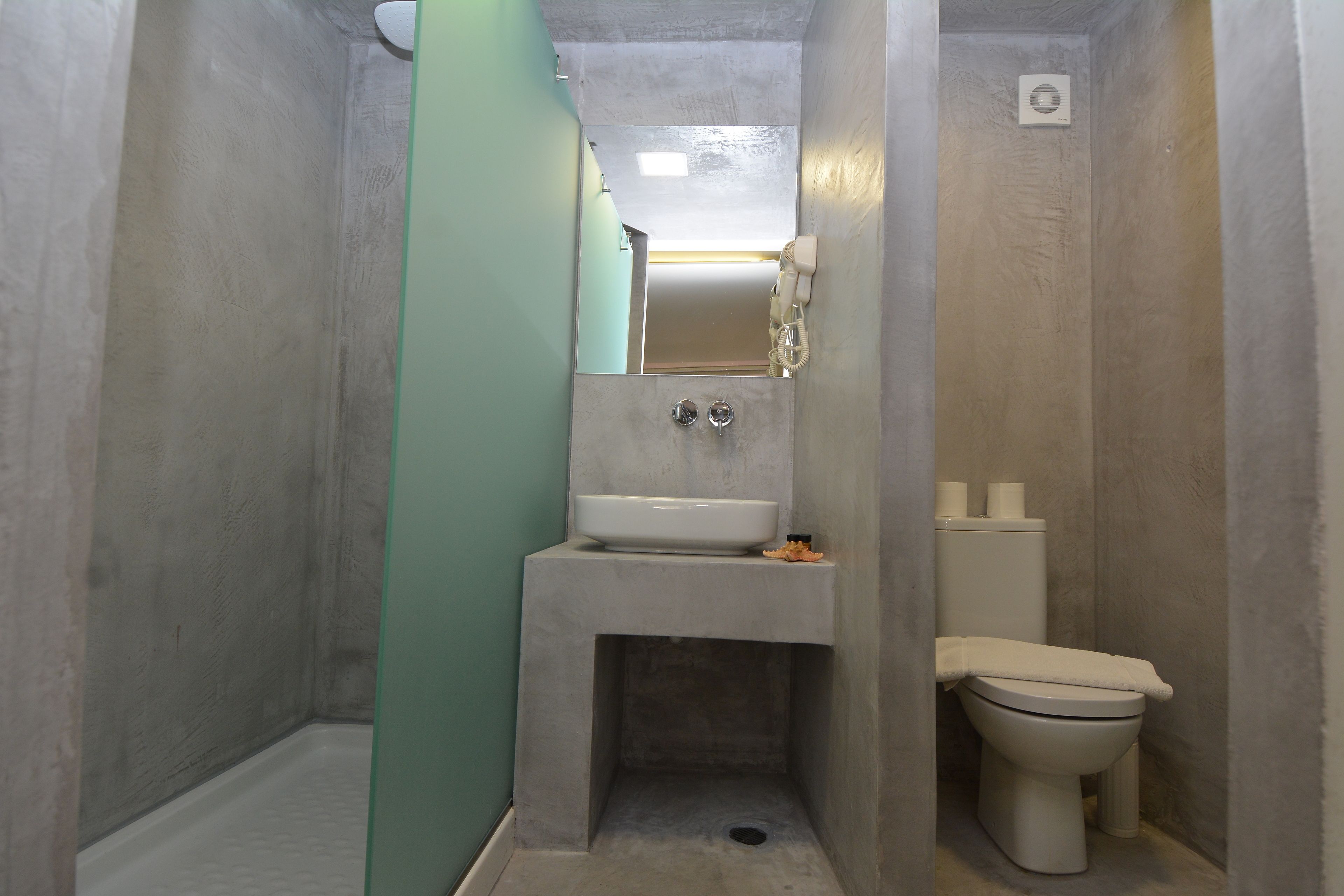 A small, narrow bathroom with a sink, toilet, and mirror.