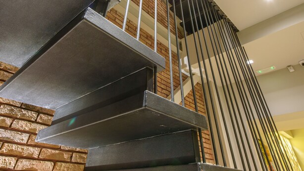 A modern staircase with metal railings and a brick wall.