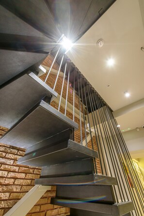 Un escalier moderne avec des rampes en métal et un mur en briques.