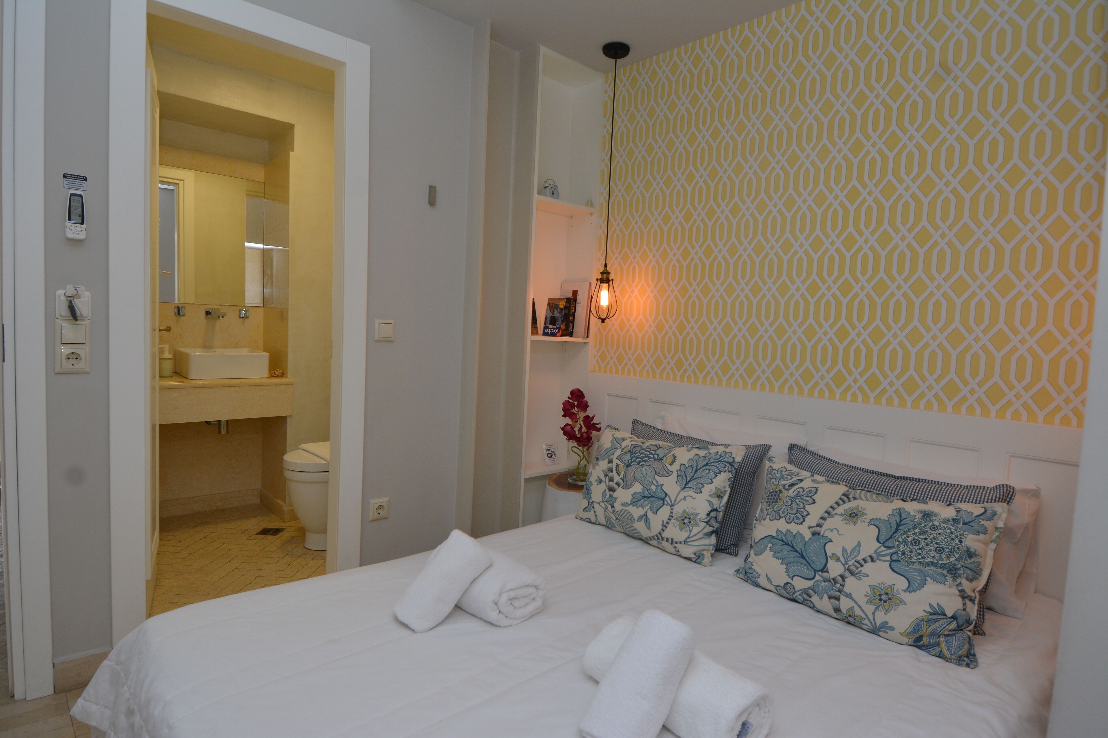 Una habitación de hotel con cama, baño y un papel tapiz estampado.