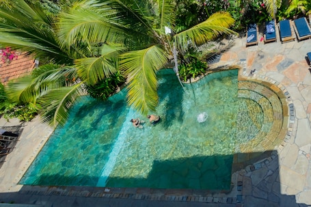 Una piscina al aire libre, sombrillas, sillones reclinables de piscina