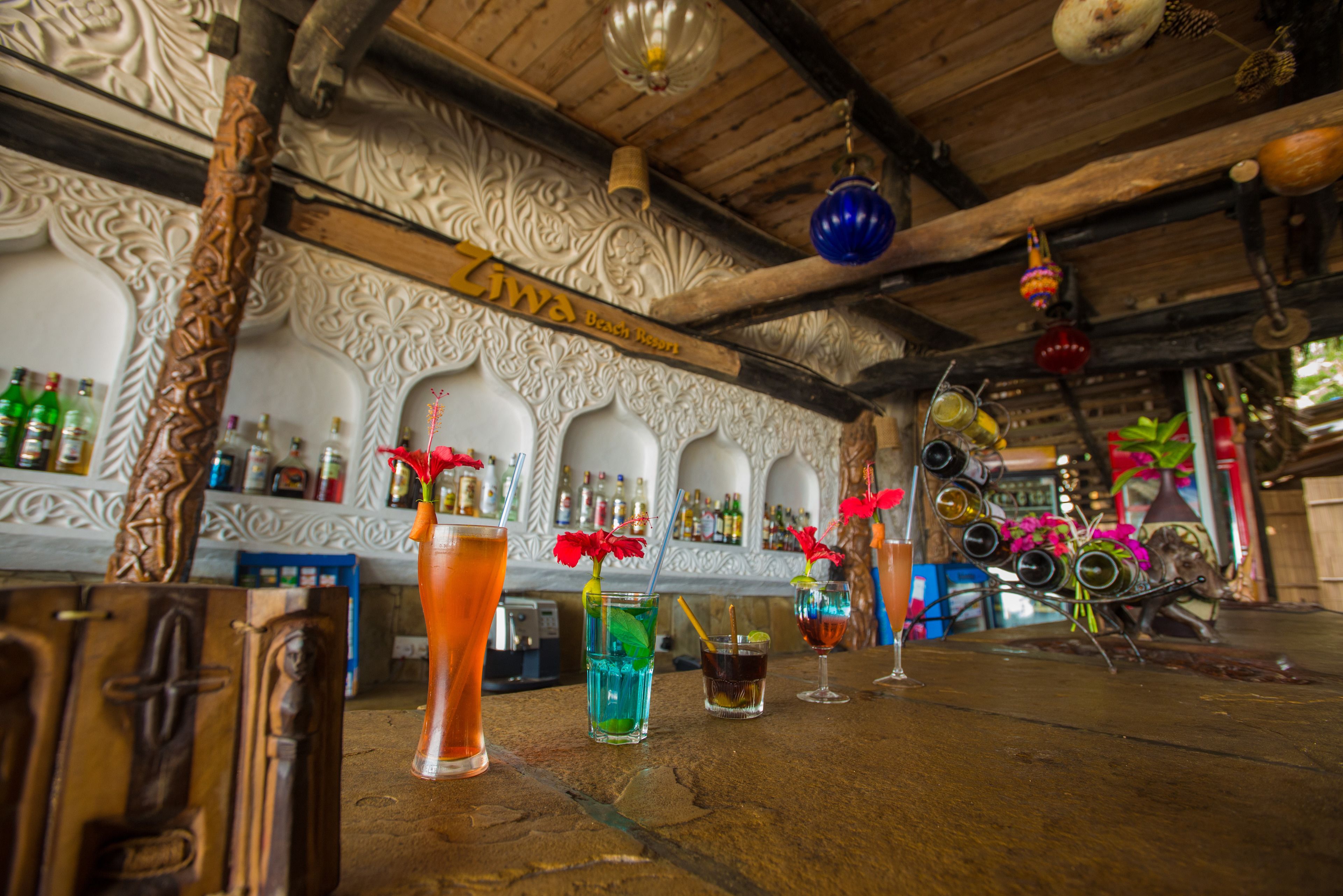 A bar area with wooden furniture, decorative wall carvings, and various bottles and glasses.