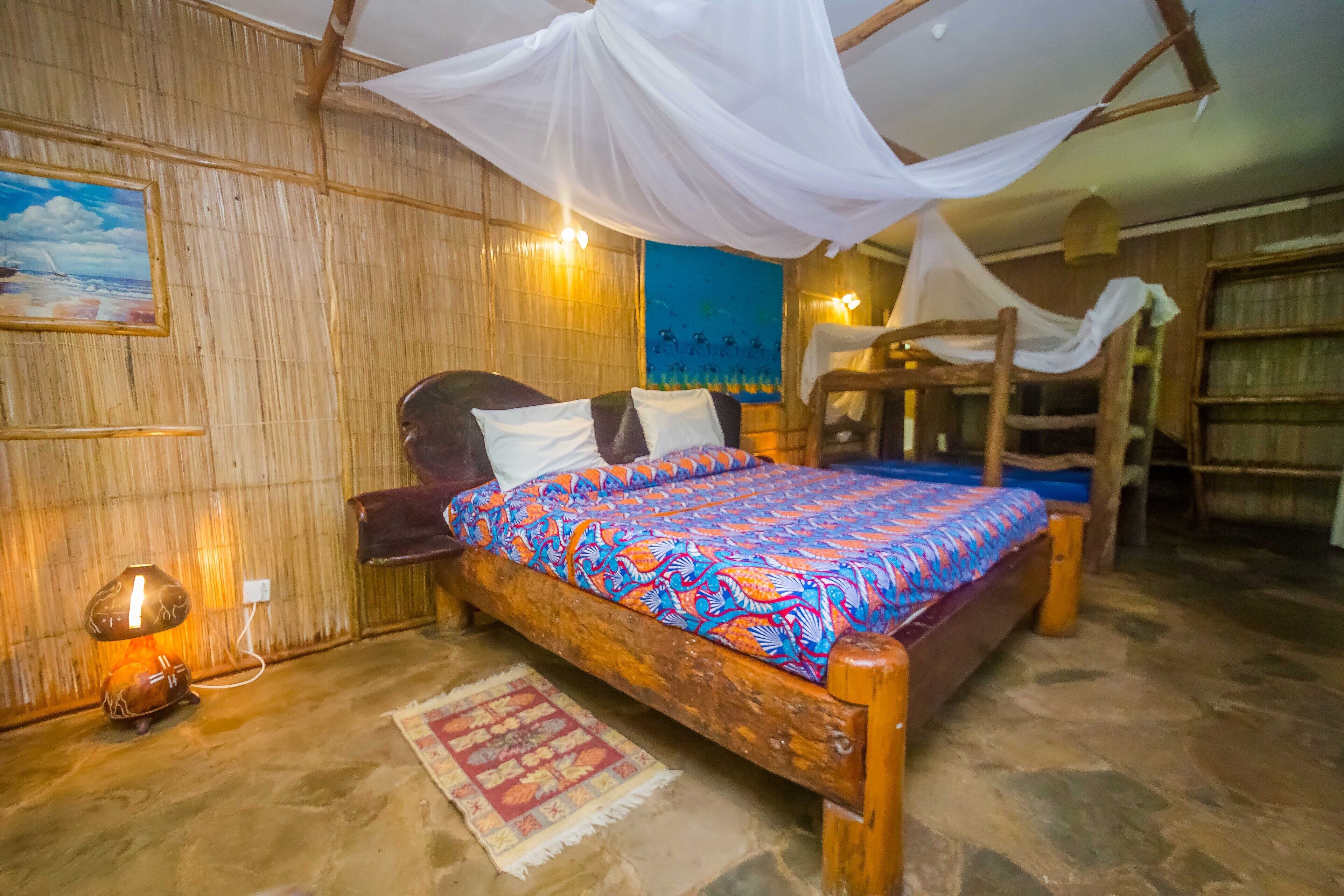 Una habitación con cama, mesita de noche, lámpara, un cuadro y una cortina.