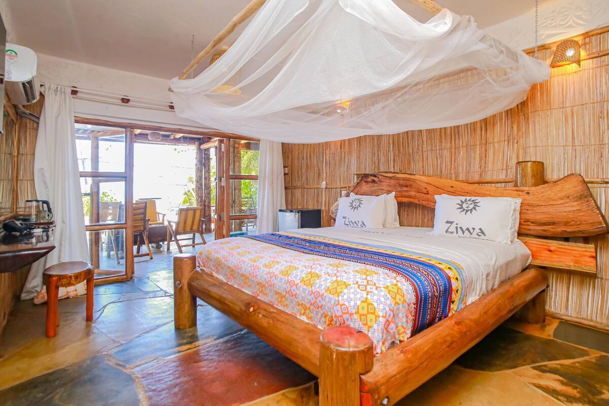 A spacious room with a large bed, wooden headboard, and a canopy.
