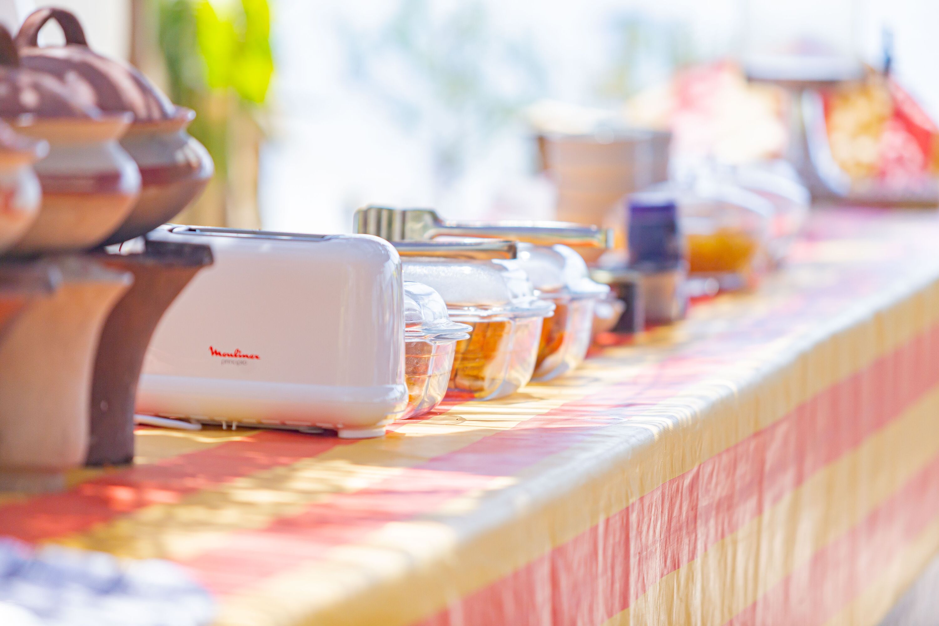 A buffet setup with various food containers and utensils on a table.