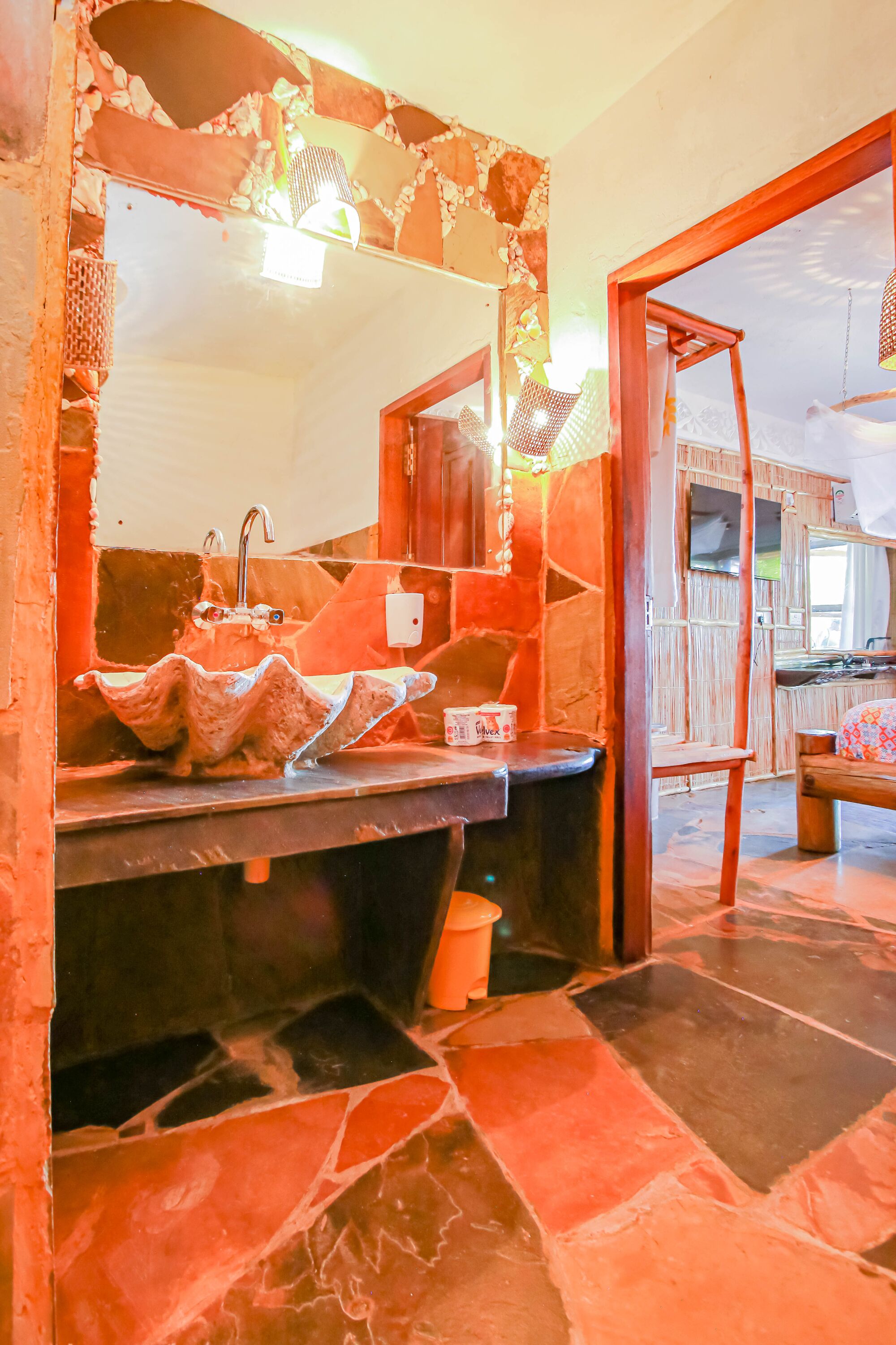 Un baño con un lavamanos de piedra, un espejo y una silla de madera.