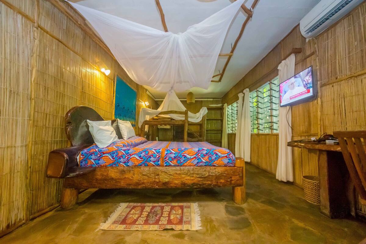 A room with a bed, a television, and a window with curtains.