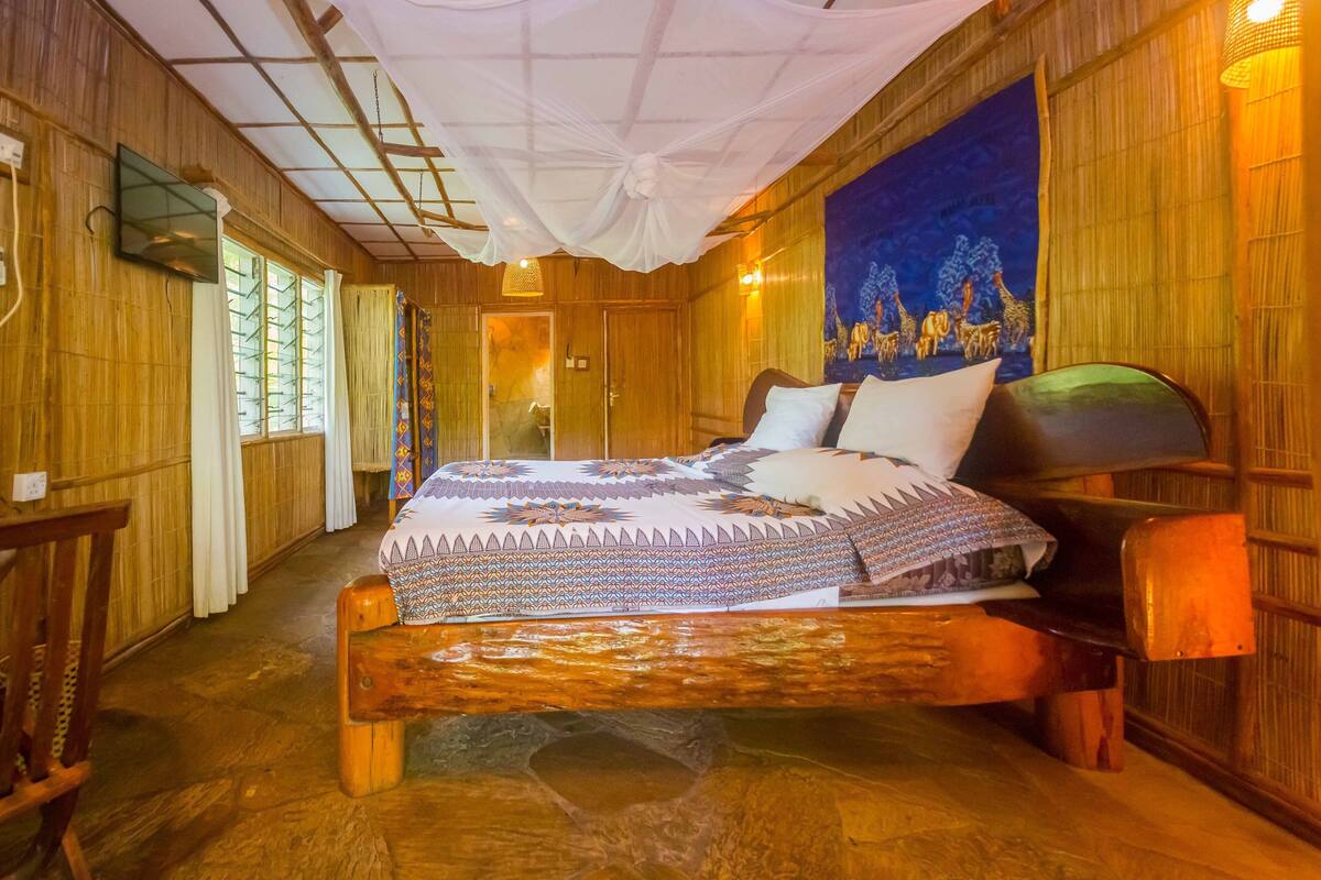 A wooden room with a bed, a window, and a tapestry on the wall.