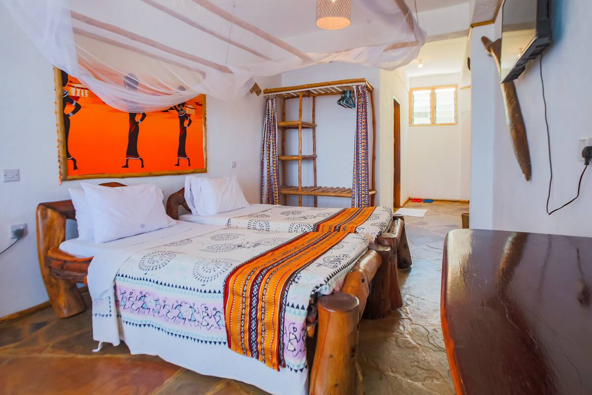 A room with a bed, wooden headboard, a ladder, and a wall-mounted TV.