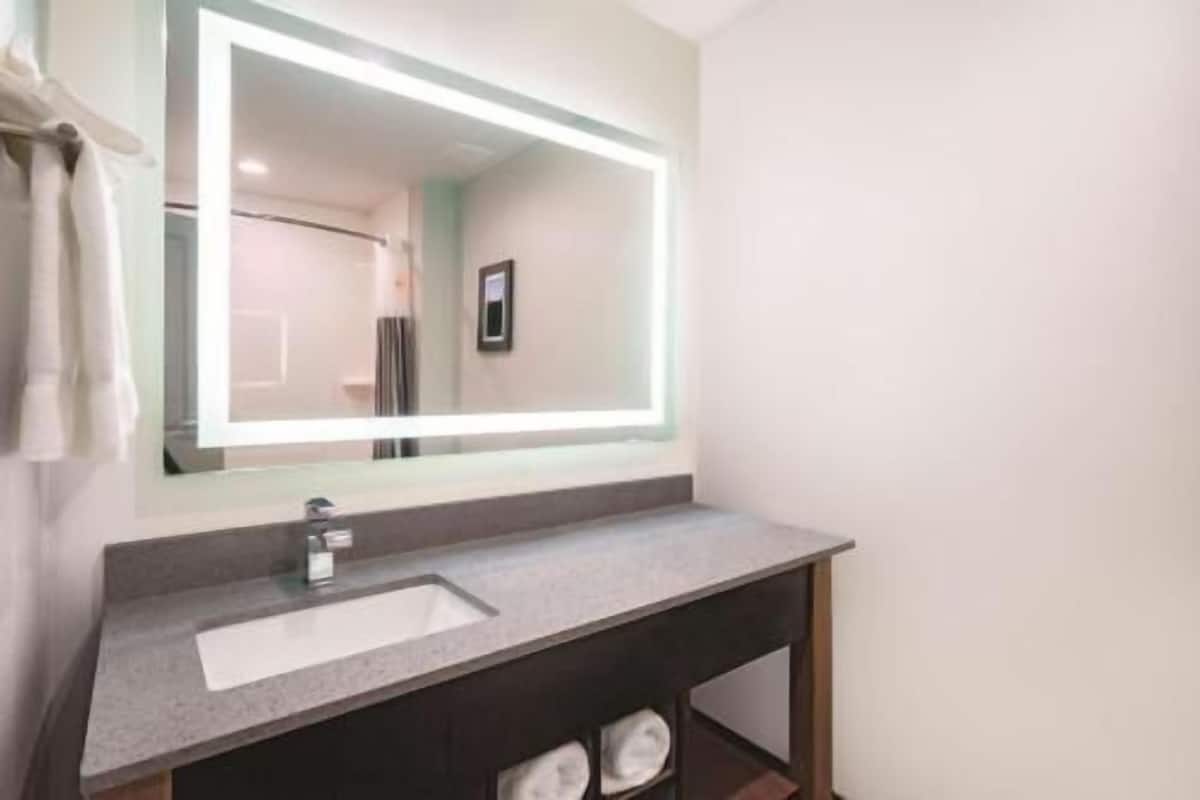 A bathroom with a large mirror, a sink, and a towel rack.