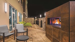 An outdoor patio with stone flooring, seating, and a built-in fire feature. - La Quinta Inn & Suites by Wyndham Cleveland near Lee Univ (Cleveland)
