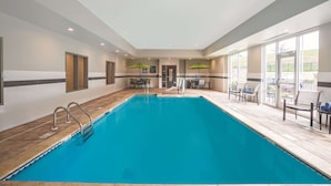 A swimming pool with a tiled deck, a reception area with a counter and chairs, and large windows allowing natural light. - La Quinta Inn & Suites by Wyndham Cleveland near Lee Univ (Cleveland)