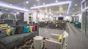 A spacious lobby with multiple seating areas, a reception desk, and a large screen. - La Quinta Inn & Suites by Wyndham Cleveland near Lee Univ (Cleveland)
