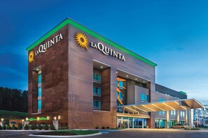A La Quinta hotel with a modern design, featuring a prominent sun logo and a covered entrance. - La Quinta Inn & Suites by Wyndham Cleveland near Lee Univ (Cleveland)