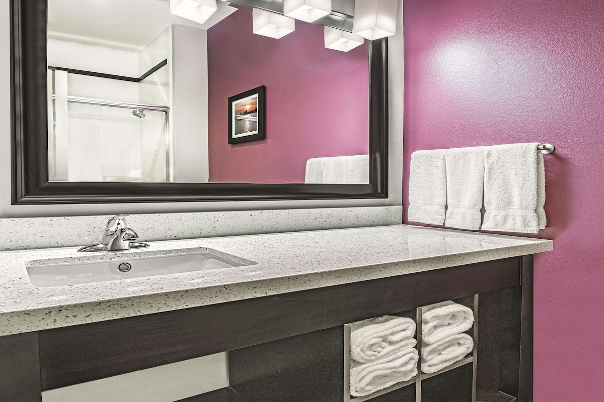 A bathroom with a large mirror, a sink, and a towel rack with multiple towels.