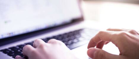 Gros plan sur des mains tapant sur le clavier d’un ordinateur portable.