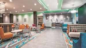 Un vestíbul modern amb zones d'estar, una recepció i un mural de paisatge urbà a la paret.
