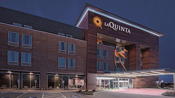 Un hotel La Quinta amb una façana moderna de maó, grans finestres i una entrada destacada amb una porta de vidre i una rampa per a accessibilitat.