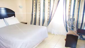 Una habitación de hotel con una cama grande, una silla, un escritorio y cortinas.