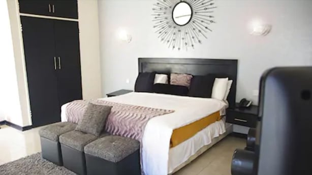 Un dormitorio con cama, mesitas de noche, armario, sofá y un reloj de pared decorativo.