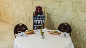 A table set for two with plates of food, wine bottles, and glasses. - Hotel Bizantino (Massafra)
