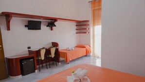 A hotel room with a bed, a desk with a chair, a small refrigerator, and a TV mounted on the wall. - Hotel Bizantino (Massafra)