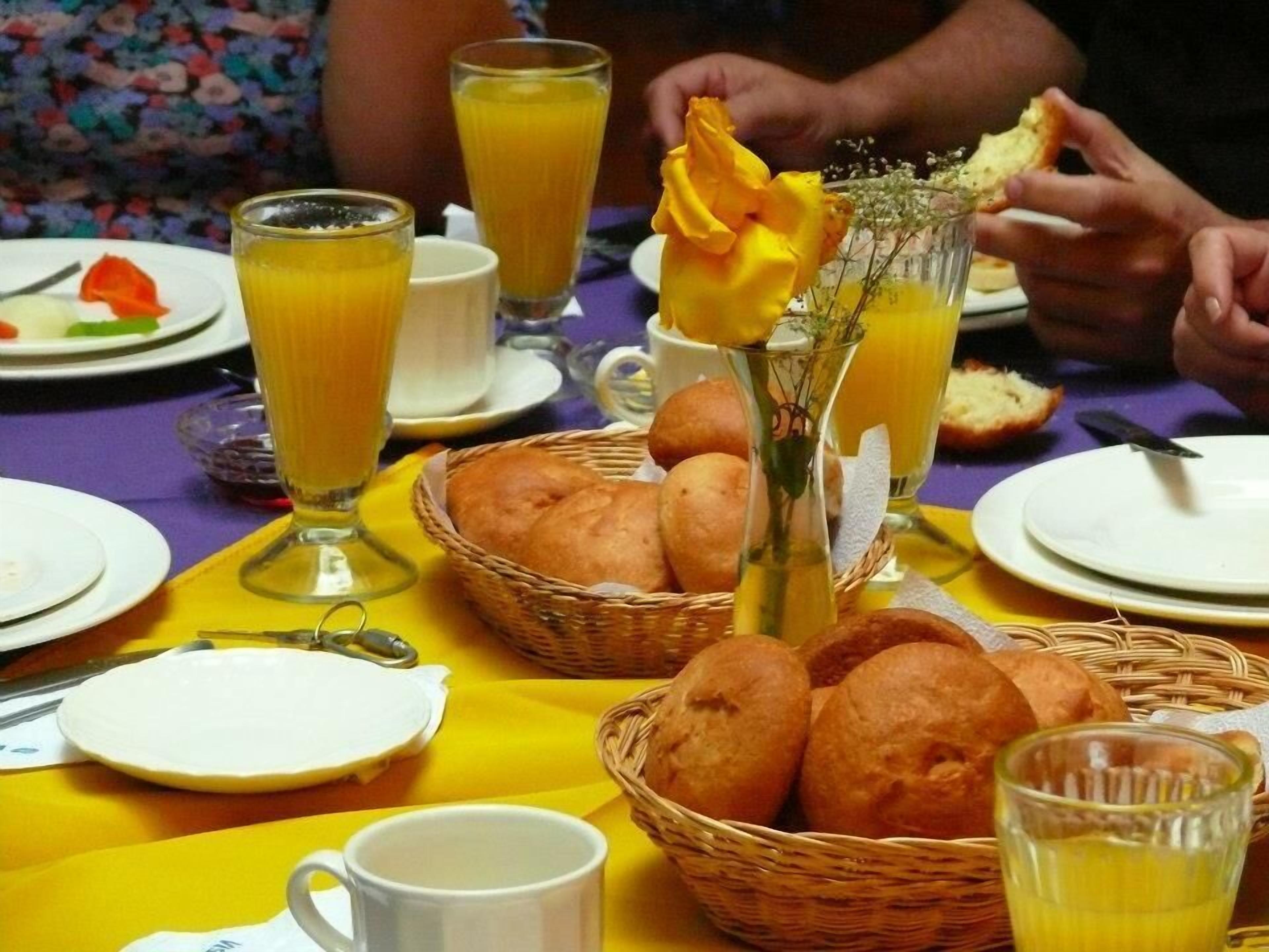 Een gedekte tafel met brood, sap en een vaas met bloemen.