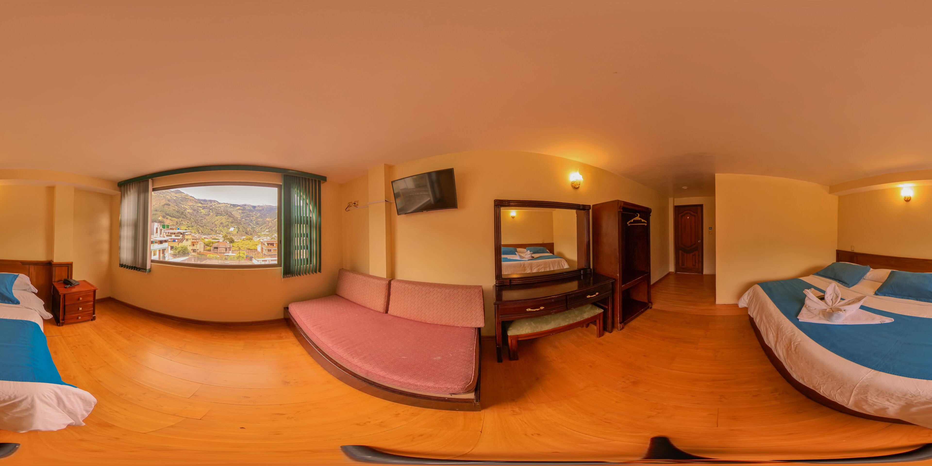 Een kamer met twee bedden, een bank, een televisie en een raam met uitzicht op een berg.