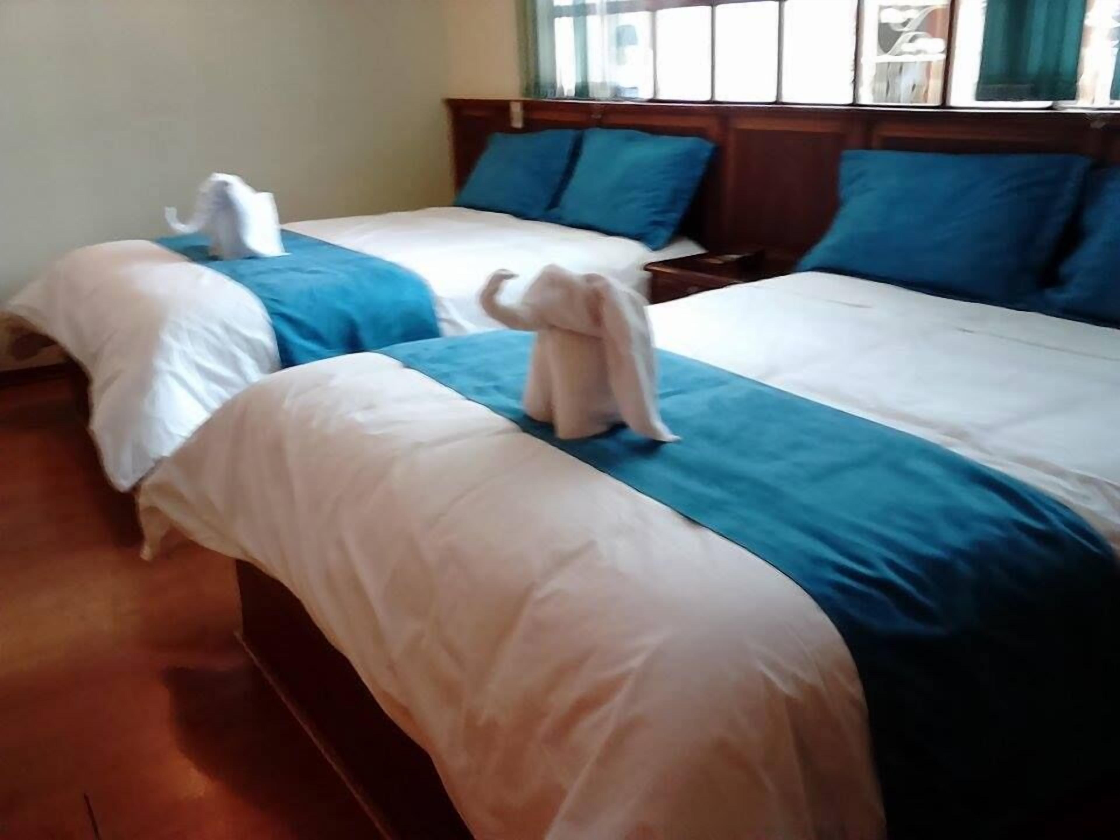 A hotel room with two beds, each with blue and white bedding, and a wooden headboard.