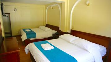 Habitación de hotel con dos camas, cada una con una colcha azul y blanca y una toalla blanca sobre la cama.
