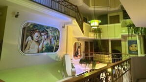 Un interior de varios niveles con una escalera, un mural y una araña.