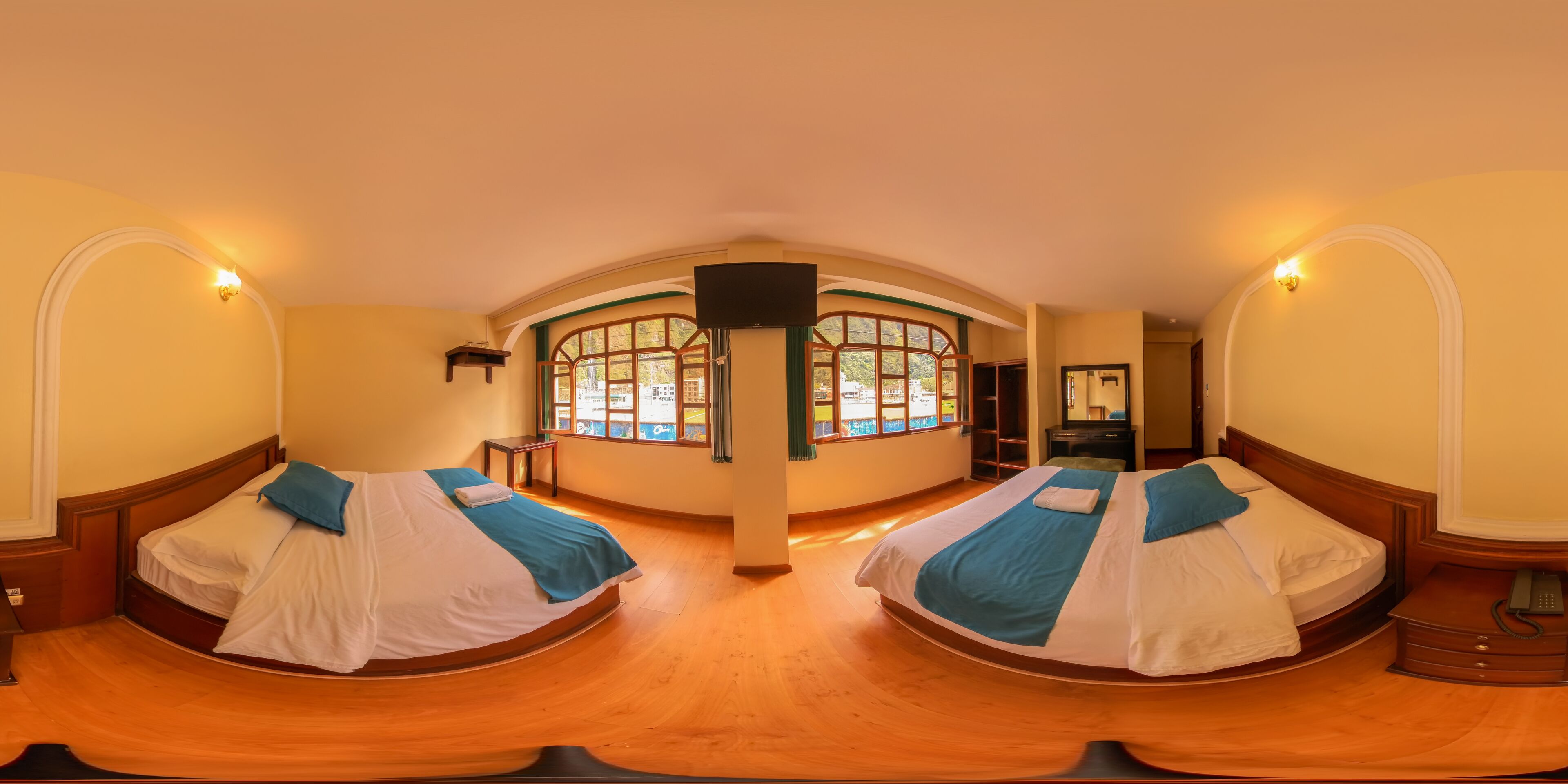 A room with two beds, a large arched window, and a flat-screen TV.