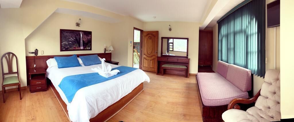 Une chambre avec un grand lit, une chaise, un bureau et une fenêtre.