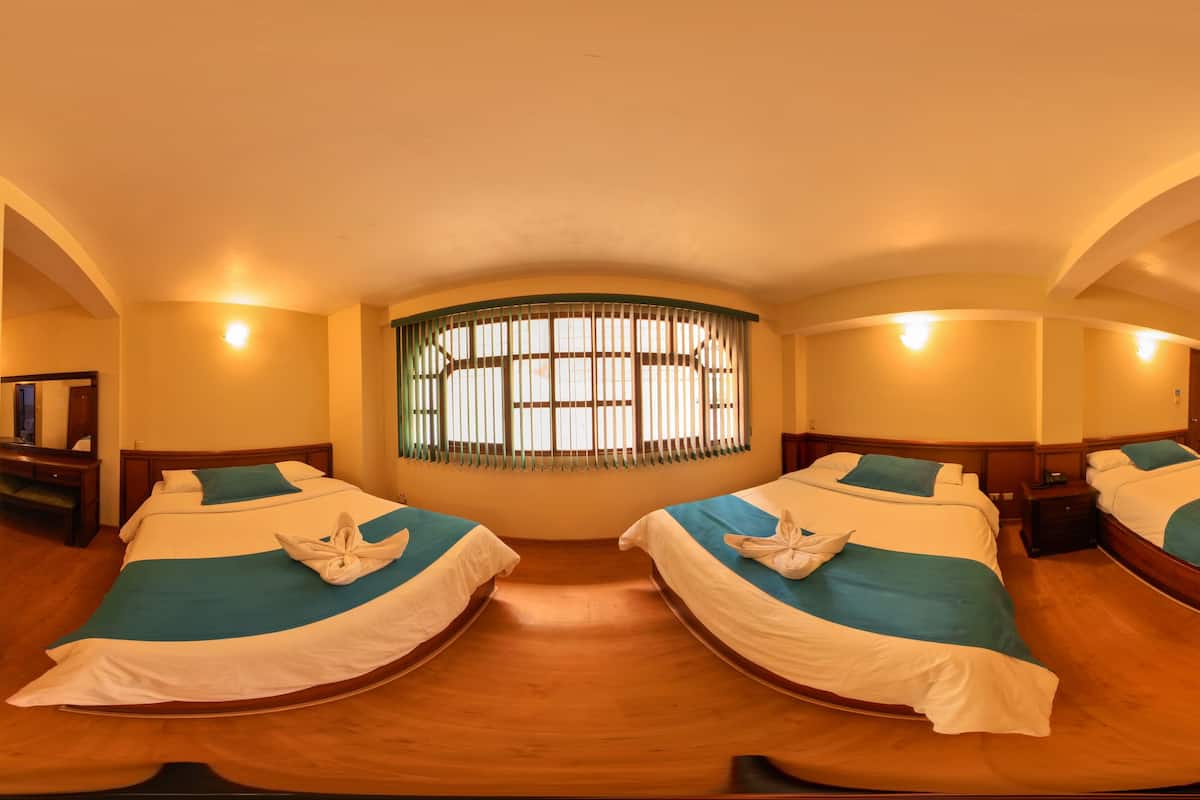 Een hotelkamer met twee bedden, een televisie, een bureau en een raam met jaloezieën.