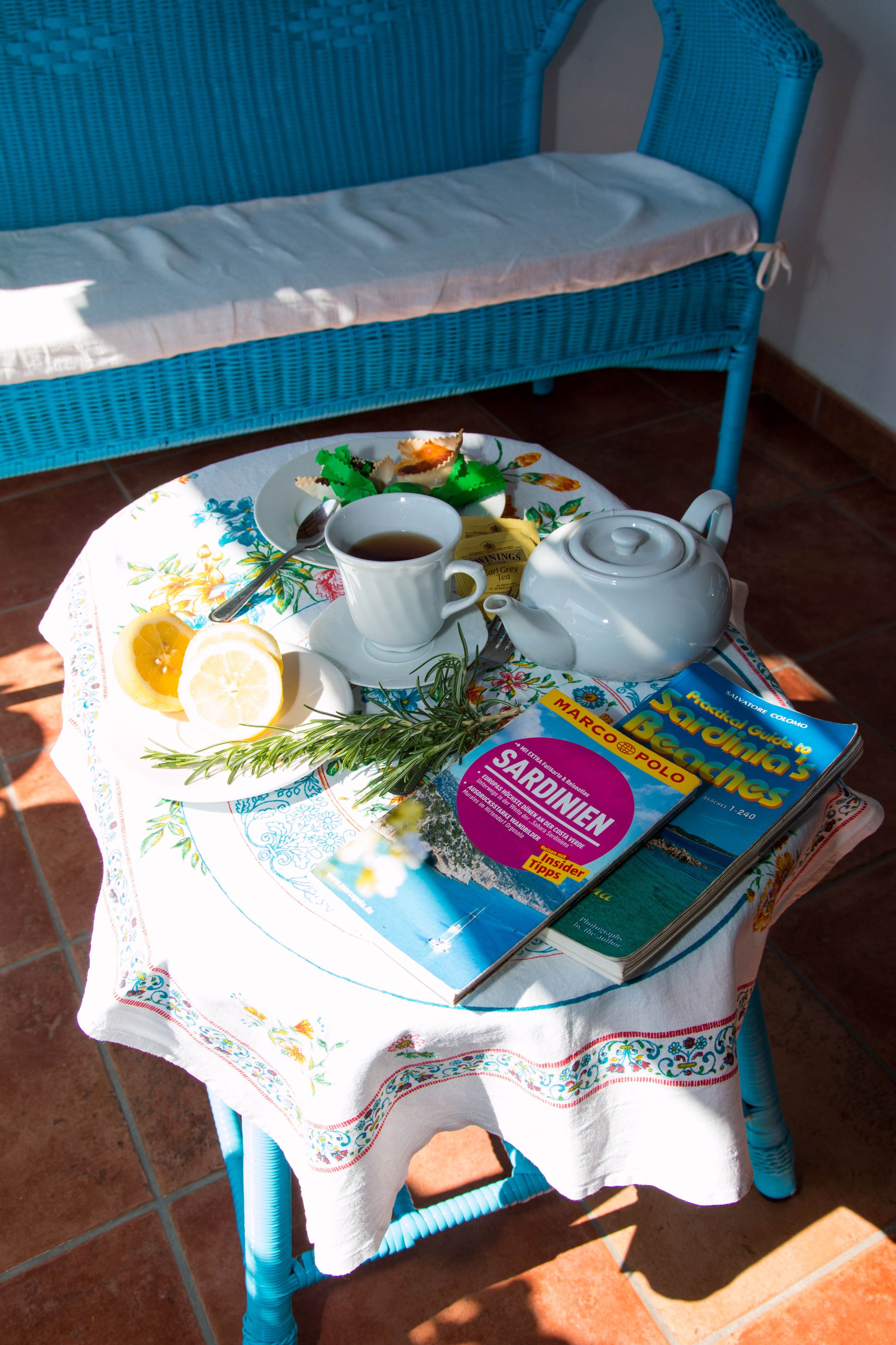 Ein Tisch mit Teekanne, Tassen, einem Buch und einem Teller mit Essen.