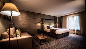 A hotel room with a bed, a sofa, a coffee table, and a lamp. - The Warwickshire Hotel and Country Club (Warwick)