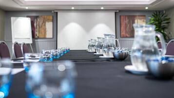 A conference room with a long table, chairs, a projector, and water pitchers.