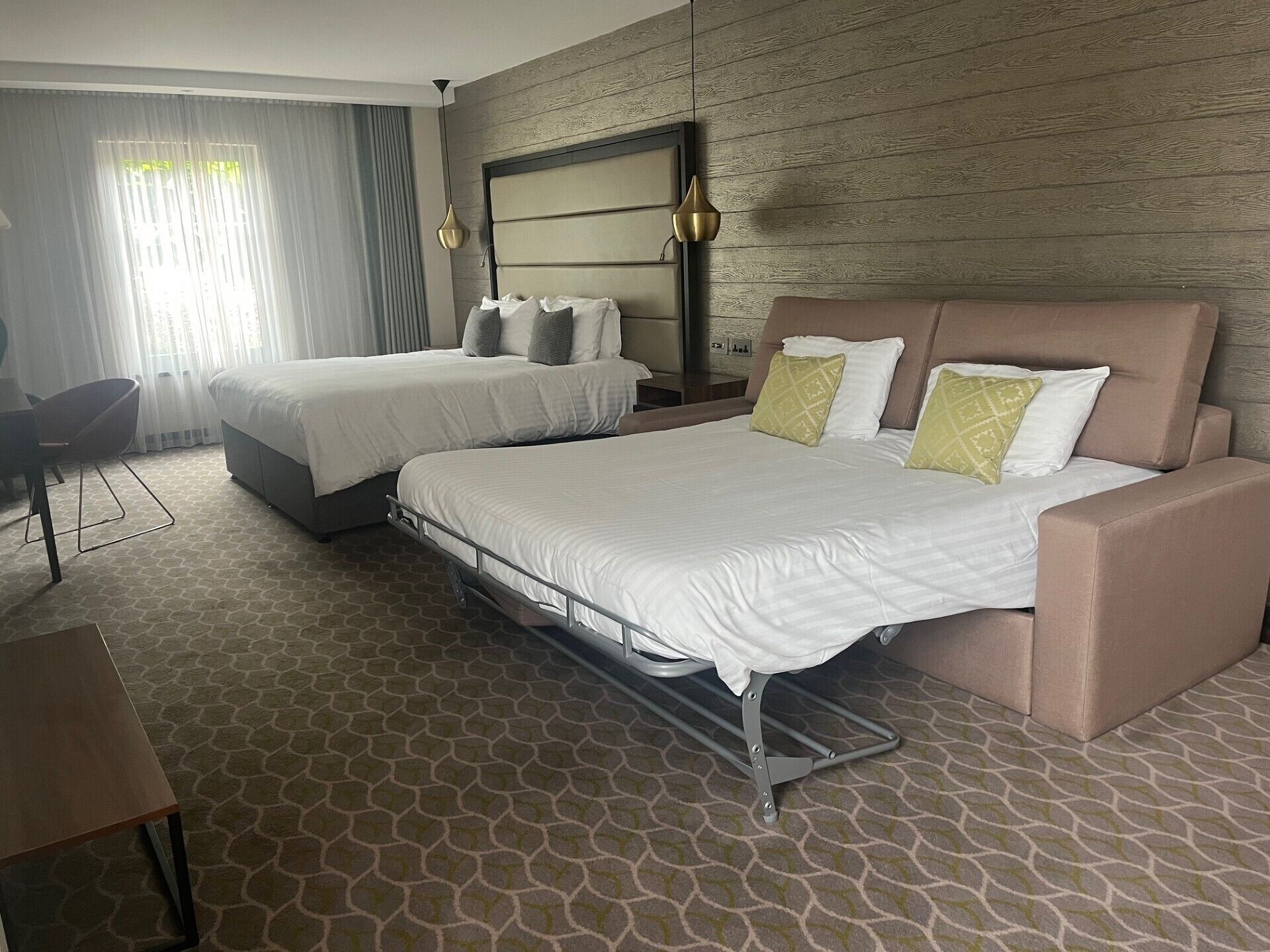 A hotel room with two beds, a desk, and a chair.