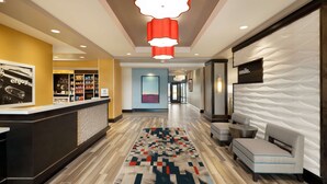 A hotel lobby with a reception desk, a patterned rug, a sofa, and a wall with a 'smile' sign.