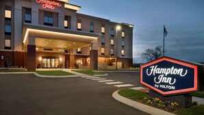 A Hampton Inn by Hilton hotel with a modern facade, large entrance, and a prominent sign.