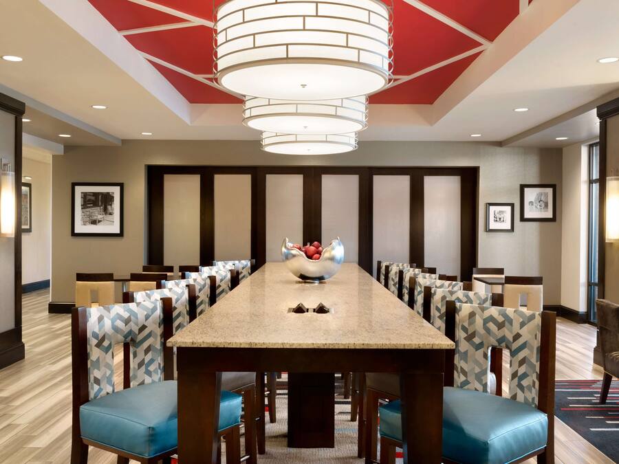 A conference room with a long table, chairs, a central fruit bowl, and a modern chandelier.