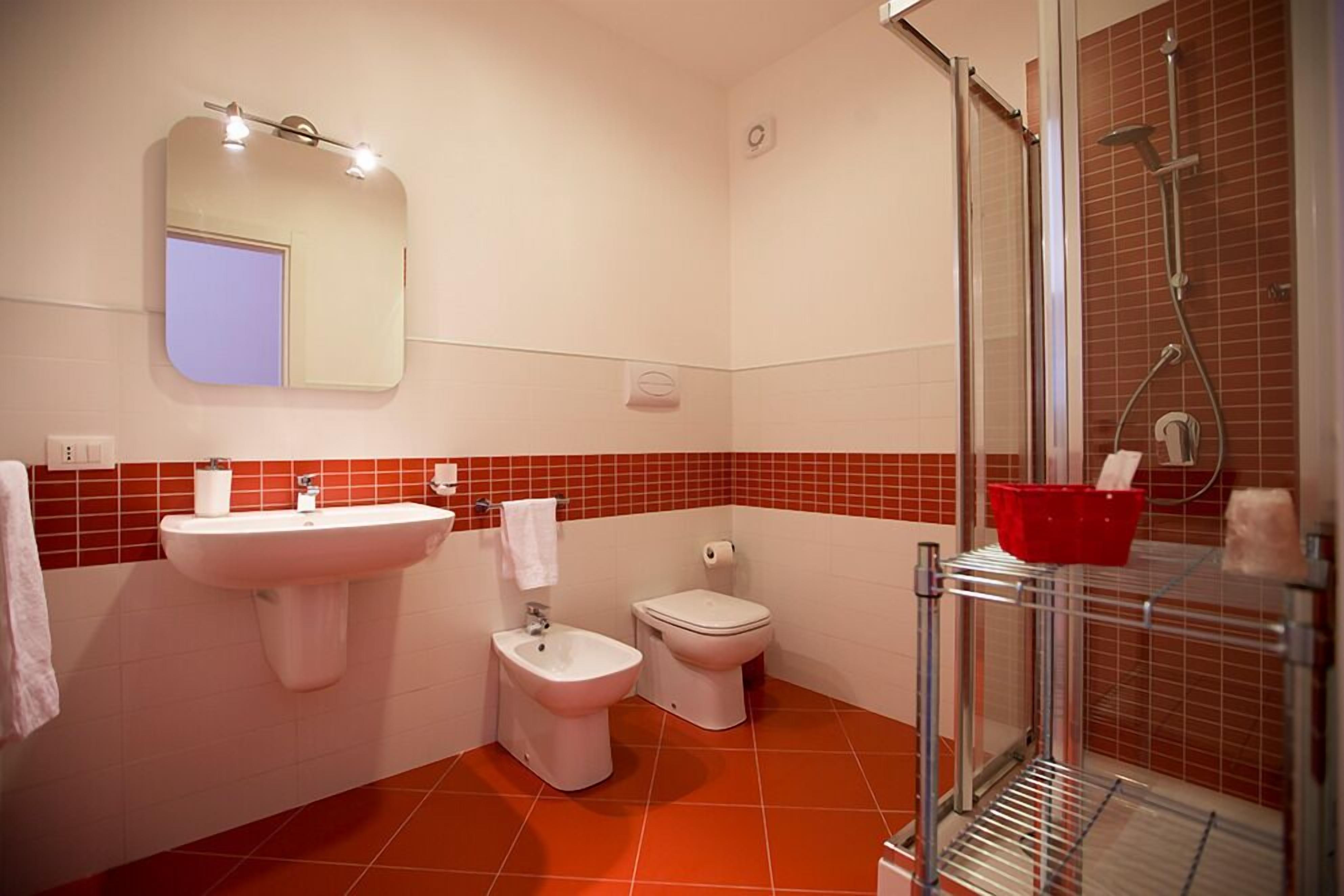 A bathroom with a sink, bidet, toilet, and a shower area.