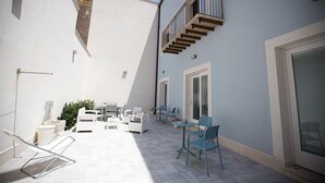 Ein Innenhof mit Außenbestuhlung, einer Treppe und einer Tür zu einem überdachten Bereich.