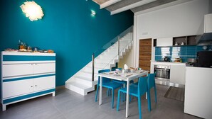 Eine moderne Küche mit weißen Schränken, einer blauen Akzentwand und einem Essbereich mit blauen Stühlen.